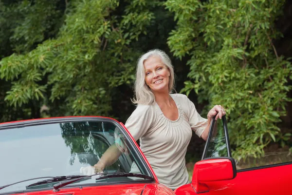 Cheerful mature woman getting off her convertible — Stock Photo, Image