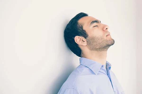 Un hombre reflexivo apoyado en una pared — Foto de Stock