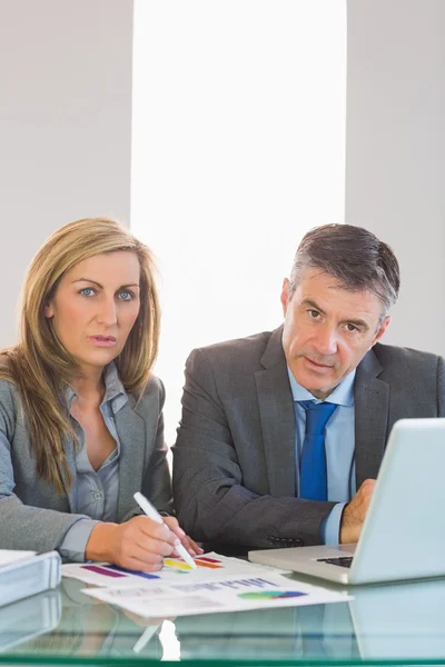 Two focused business people looking at camera trying to understand figures — Stock Photo, Image