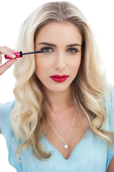 Ernstige blonde model in blauwe jurk toepassing van mascara — Stockfoto