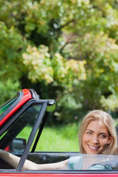 ผู้หญิงผมบลอนด์มีความสุข ขับรถแคบริโอเลตสีแดง — ภาพถ่ายสต็อก