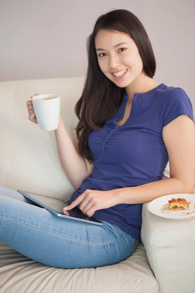 Jeune femme asiatique heureuse en utilisant sa tablette pc et tenant tasse de café — Photo