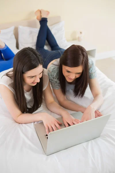 Amis utilisant un ordinateur portable couché sur le lit — Photo