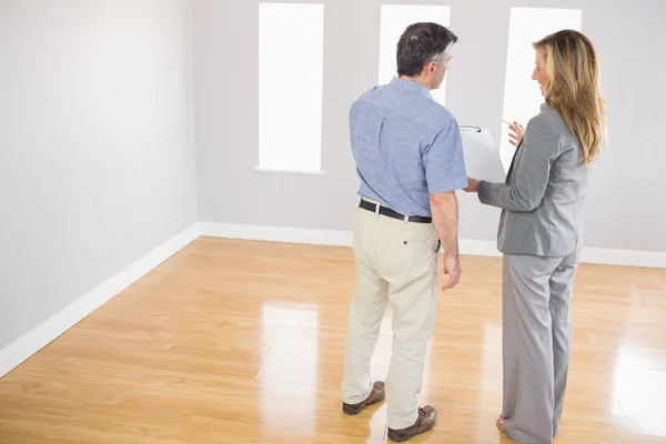 Blonde realtor showing a room and some documents to a potential buyer — Stock Photo, Image