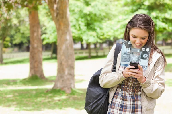 Uśmiechnięta młoda kobieta SMS-y na jej futurystyczny smartphone — Zdjęcie stockowe