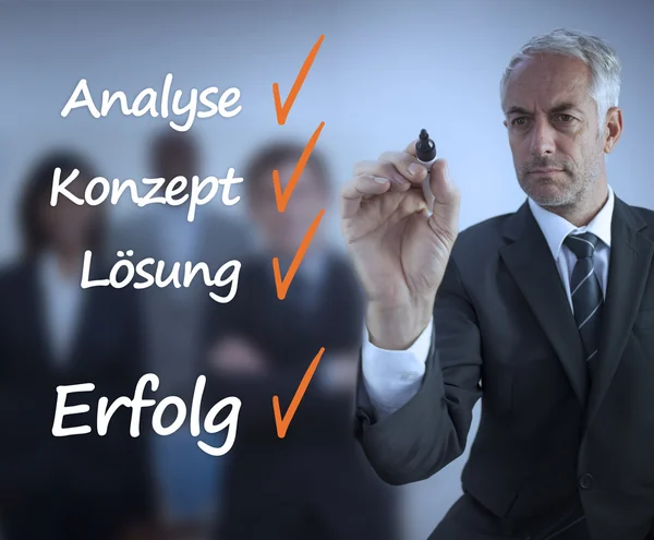 Businessman writing a success checklist in german — Stock Photo, Image