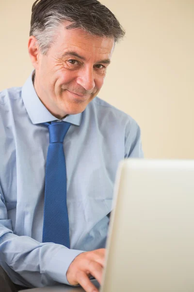 Homem satisfeito usando um laptop sentado em uma cama — Fotografia de Stock