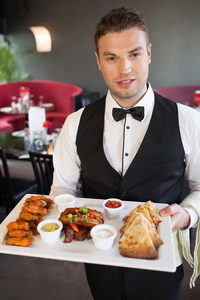 Handsome waiter serving appetizing finger food platter — Stock Photo, Image