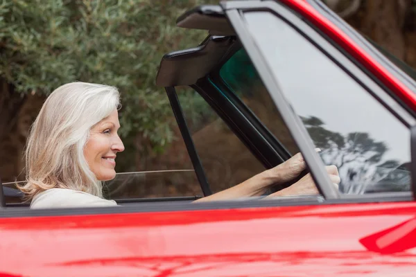 Счастливая зрелая женщина водит красный кабриолет — стоковое фото