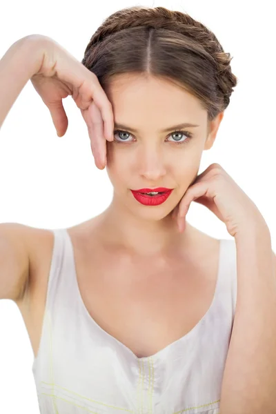 Modelo sonriente en vestido blanco posando tocando su sien y su mejilla — Foto de Stock