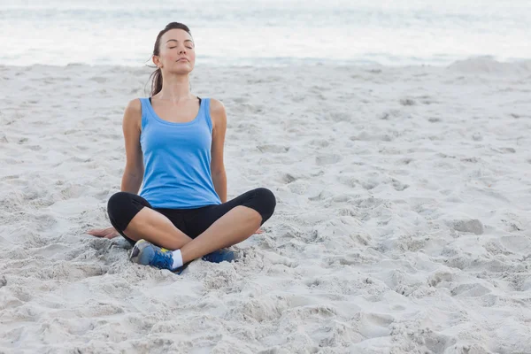 Брюнетка, сидящая после спорта на пляже — стоковое фото