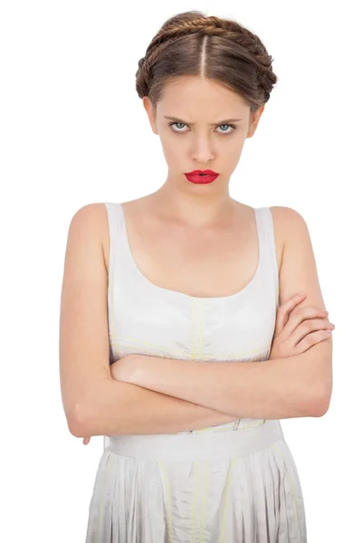 Modelo frunciendo el ceño en vestido blanco posando con brazos cruzados — Foto de Stock