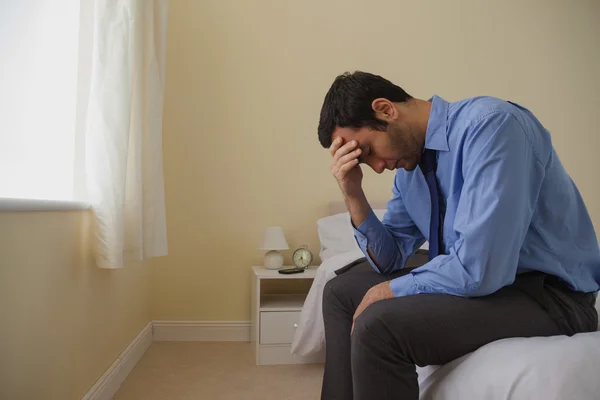 Mournful man sitting head in hands on his bed — Stock Photo, Image