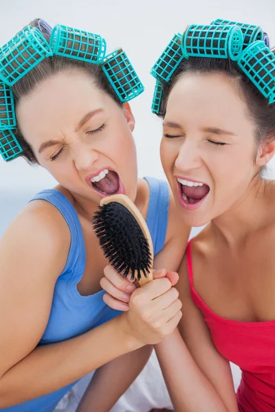 Friends in hair rollers holding hairbrush — Stock Photo, Image