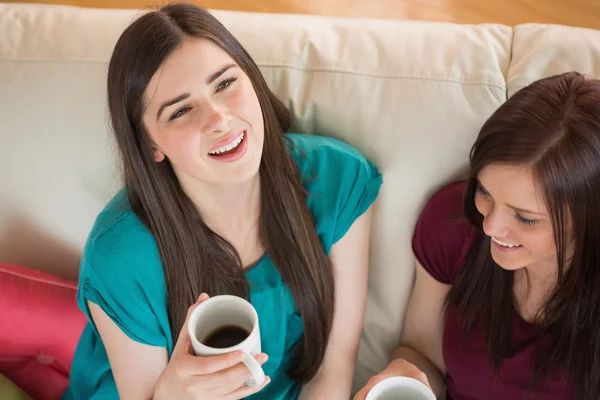 Dois amigos rindo tomando café no sofá — Fotografia de Stock