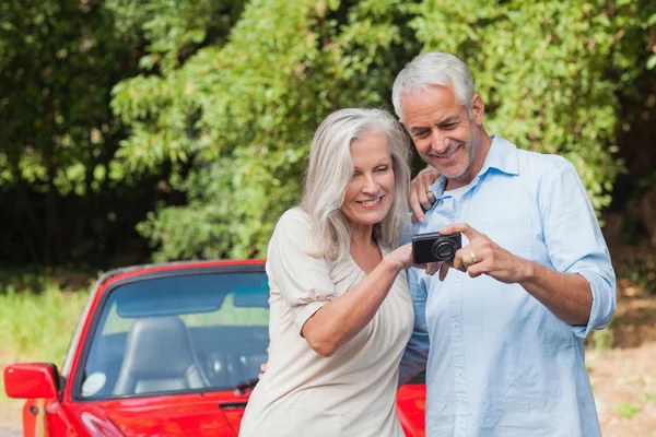 Alegre pareja madura mirando fotos en su cámara — Foto de Stock