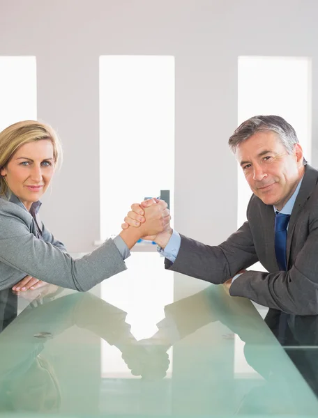 Two smiling businesspeople having a showdown sitting around a table — Stock Photo, Image