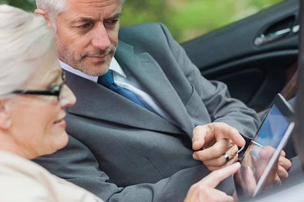 Parceiros trabalhando juntos no tablet no conversível elegante — Fotografia de Stock