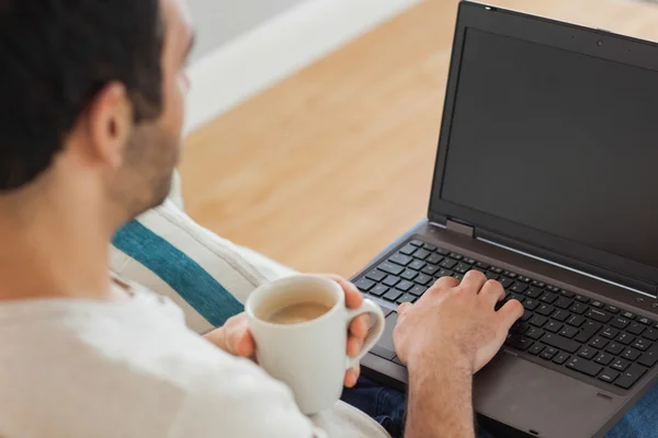 Braunhaariger Mann hält Kaffee mit seinem Laptop — Stockfoto