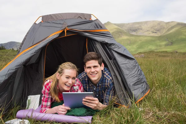 Coppia sorridente sdraiata nella loro tenda e utilizzando tablet digitale — Foto Stock