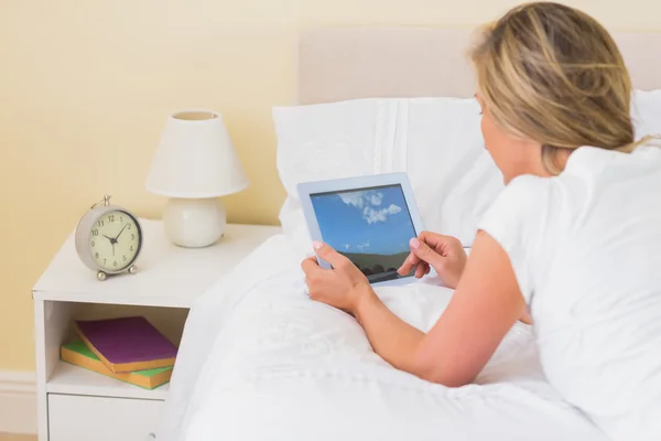 Geconcentreerd vrouw met behulp van een tablet pc liggend op haar bed — Stockfoto