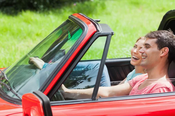 Jeune couple souriant faisant un tour en cabriolet rouge — Photo