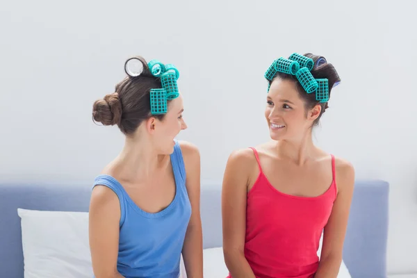 Girls wearing hair rollers sitting in bed — Stock Photo, Image
