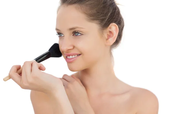 Pleased brunette model applying powder on her cheek — Stock Photo, Image