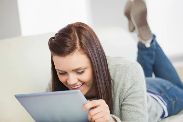 Avslappnad tjej söker och använder en TabletPC på en soffa — Stockfoto