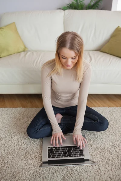 Blonde vrouw zittend op de vloer met behulp van laptop — Stockfoto