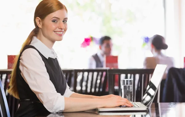 Mulher de negócios sorrindo trabalhando no laptop olhando para a câmera — Fotografia de Stock