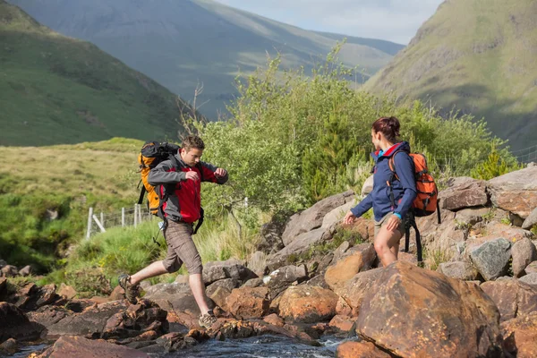 Koppel een rivier oversteken op een wandeling — Stockfoto