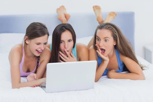 Grils on bed looking at laptop — Stock Photo, Image