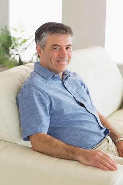 Smiling man sitting on a sofa — Stock Photo, Image