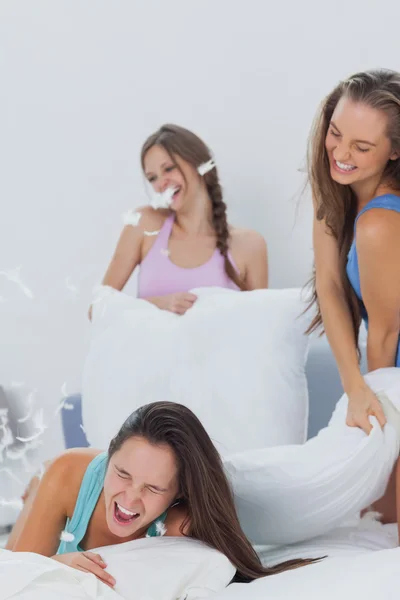 Laughing friends having pillow fight in bed — Stock Photo, Image