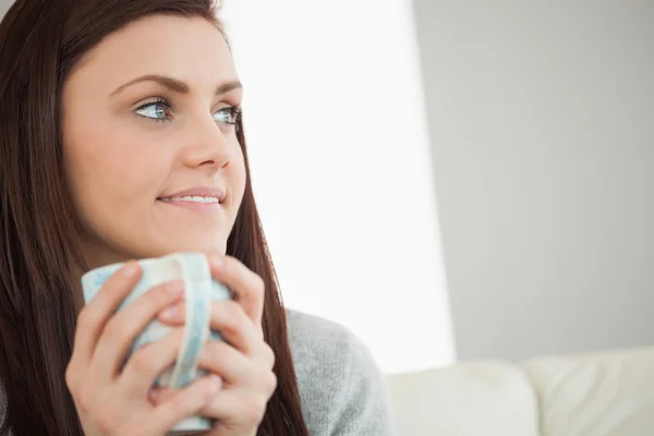 Menina cuidadosa segurando uma xícara de café e olhando para longe — Fotografia de Stock