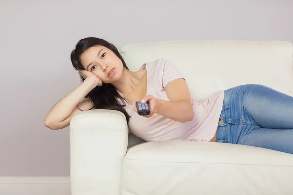 Annoiato asiatico ragazza sdraiato su il divano guardando tv — Foto Stock