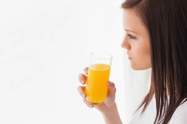 Nachdenkliches Mädchen hält ein Glas Orangensaft in der Hand und schaut weg — Stockfoto