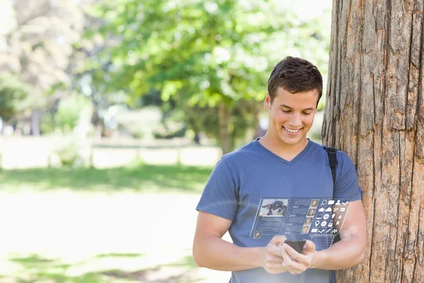 Wesoły przystojny student za pomocą jego cyfrowy smartphone — Zdjęcie stockowe