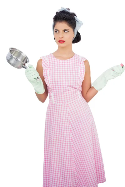 Puzzled black hair model holding a pan and wearing rubber gloves — Stock Photo, Image