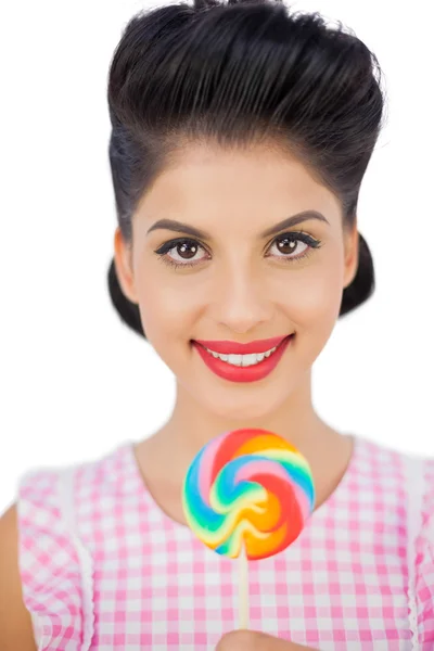 Alegre modelo de pelo negro sosteniendo una piruleta de colores — Foto de Stock