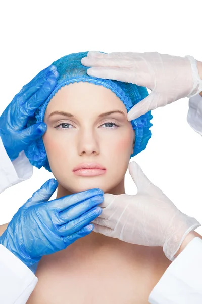 Cirurgiões examinando loira relaxada vestindo boné cirúrgico azul — Fotografia de Stock