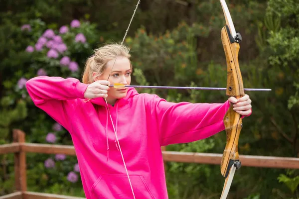 Konzentrierte Blondine übt sich im Bogenschießen — Stockfoto