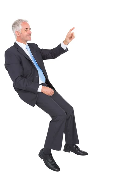 Hombre de negocios sonriente sentado y señalando con el dedo —  Fotos de Stock