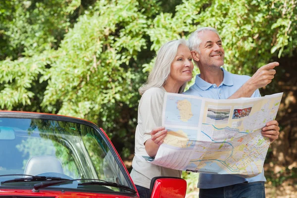 Alegre pareja madura lectura mapa en busca de dirección — Foto de Stock