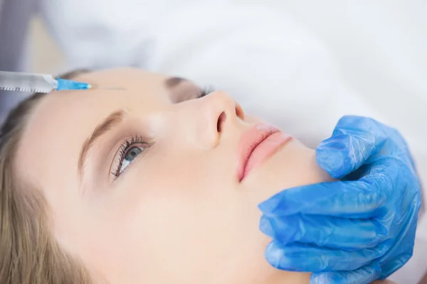 Surgeon making injection on forehead on calm woman lying — Stock Photo, Image