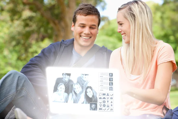 Lächelndes junges Paar beim gemeinsamen Betrachten von Fotos auf digitaler Schnittstelle — Stockfoto