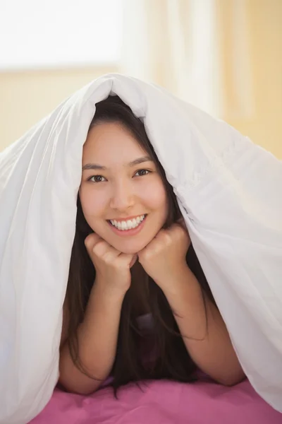 Bonito jovem ásia mulher sob ela edredom sorrindo no câmara — Fotografia de Stock