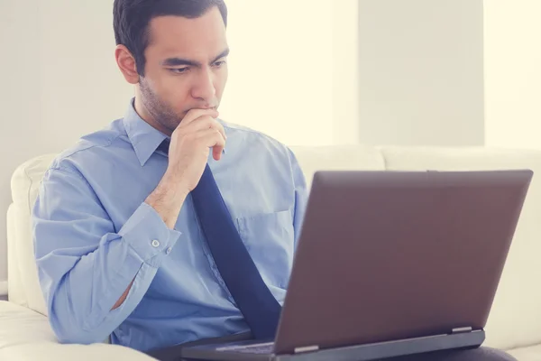 Stressad man använder en bärbar dator som sitter på en soffa — Stockfoto