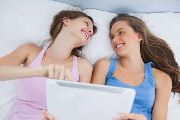 Amigos deitados na cama com tablet — Fotografia de Stock